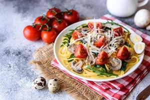 Spaghetti with mushrooms, cheese, spinach, rukkola and cherry tomatoes photo