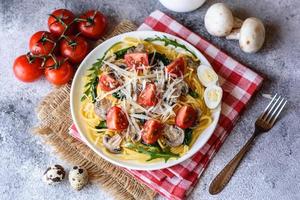 Spaghetti with mushrooms, cheese, spinach, rukkola and cherry tomatoes photo