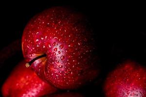 Fresh juicy red apple with droplets of water against dark background photo