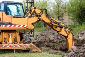 The modern excavator performs excavation work on the construction site photo