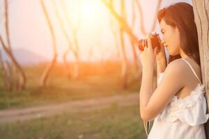 Beautiful young woman shooting with retro camera photo