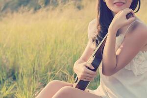 Bella mujer sentada mano abraza el violín en la pradera foto