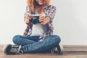 Young hipster photographer woman taking photo and look at camera