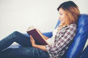 Woman reading books and lying in sofa at home. photo