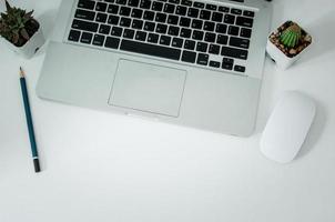 Top view computer laptop and pencil cactus on white background photo