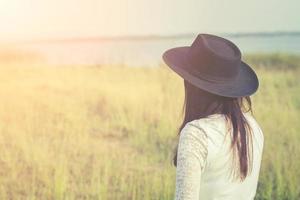 Sad woman wearing black hat standing in a meadow photo