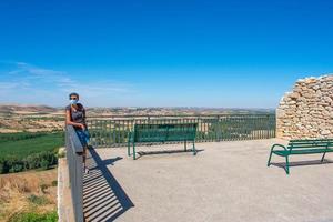 woman wearing a mask looking at the plain from a lookout point photo