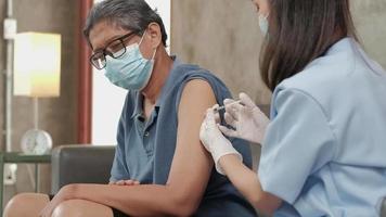 kvinnlig läkare vaccinerar en äldre man hemma