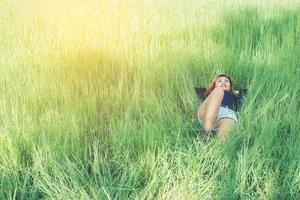 Beautiful young woman lying down on green grass enjoying life and happy photo