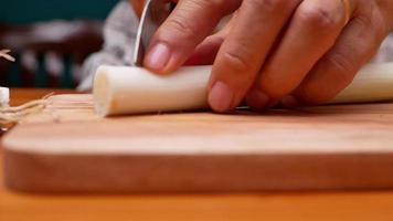 main féminine à l'aide d'un couteau de cuisine pour couper l'oignon long japonais video