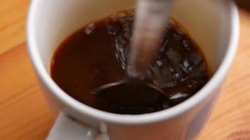 bovenaanzicht van de hand van de persoon die zwarte koffie roert met een lepel video