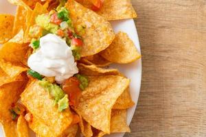 Mexican nachos tortilla chips with jalapeno, guacamole, tomatoes salsa and dip photo