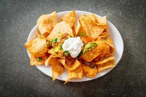 Mexican nachos tortilla chips with jalapeno, guacamole, tomatoes salsa and dip photo