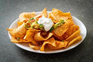 Mexican nachos tortilla chips with jalapeno, guacamole, tomatoes salsa and dip photo