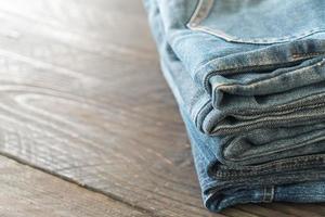 Stacks of jeans clothing on wood background photo