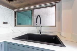 Luxurious modern black sink on a marble kitchen countertop at house photo