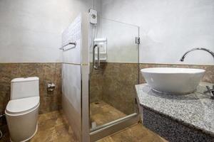 Baño blanco moderno y de madera con cabina de ducha de vidrio en el apartamento foto