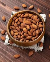 Almonds in wooden bowl on the table, Healthy snack, Vegetarian food photo