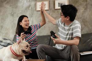 pareja asiática está jugando videojuegos y un perro mascota cerca.