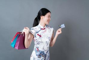 Mujer asiática vistiendo traje tradicional chino con bolsa de compras y tarjeta foto