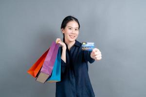 Hermosa mujer asiática con bolsas de la compra y mostrando tarjeta de crédito foto