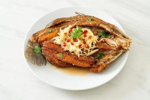 Lubina frita con salsa de pescado y ensalada picante foto