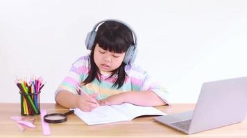 Estudiante asiática usando audífonos estudiando en línea desde casa video