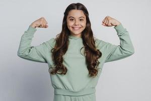 Smiling girl shows biceps. The girl raised her hands up photo