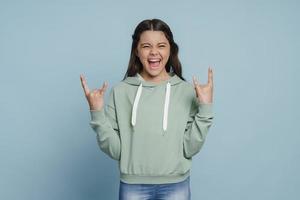 Cheerful, smiling girl shows a rock and roll gesture photo