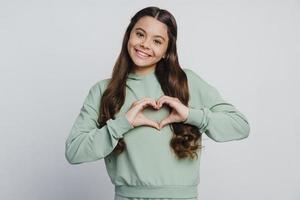 Attractive, cute teenage girl shows a gesture from the heart photo