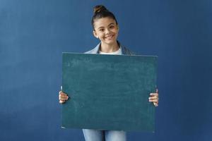 Attractive teenage girl holding a blank blue paper photo