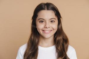 Smiling, positive teenage girl posing on a brown background photo