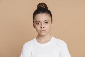 Serious teenage girl with a bundle of hair looks at the camera photo