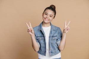Positive, smiling teenage girl showing V gesture