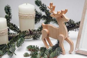 Three Christmas candles, branch of pine and wooden deer photo