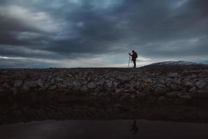 silueta de un fotógrafo o viajero con trípode de pie sobre piedra foto