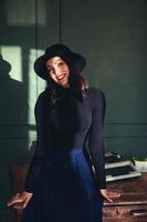 Beautiful woman in a hat sits near oak table with vintage typewriter photo