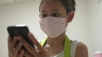 Girl Wears Face Mask While Using Smartphone for Online Communication at Home video