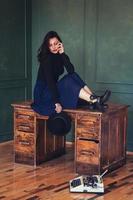 Beautiful woman in a hat sits near oak table with vintage typewriter photo