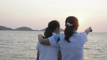 madre abraza a su hija y hermosos paisajes en el mar durante el amanecer video