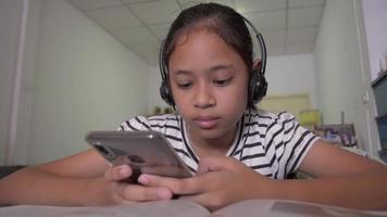 jolie fille regardant une vidéo en ligne à partir d'un téléphone intelligent avec un casque à la maison video