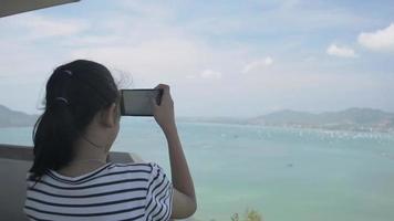 Jovencita sosteniendo teléfono móvil tomando fotos en la torre del punto de vista video