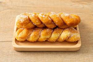 Sugar doughnut in a spiral shape on wooden plate photo