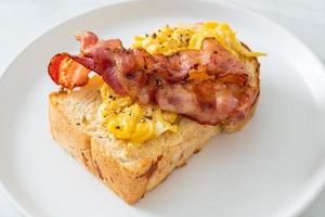 Bread toast with scramble egg and bacon on white plate photo