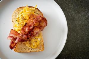 Bread toast with scramble egg and bacon on white plate photo