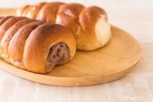 Bread roll with cream on wood plate photo