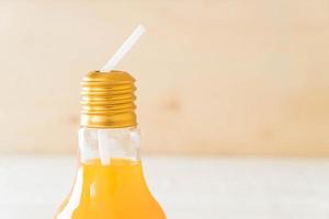 Orange juice in lamp shape glass on wood photo