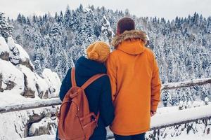 Couple with backpacks enjoying mountain view during winter vacation photo