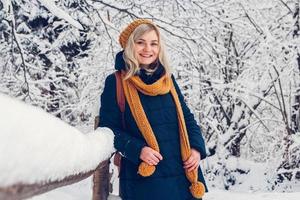 Beautiful young girl in a winter park walks in the winter forest photo