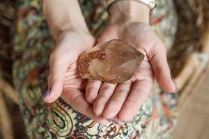 Woman holding a large, luminous quartz crystal appears powerful